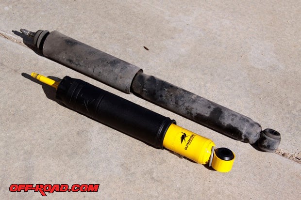 The factory Toyota shock absorber is shown next to the new Old Man Emu Nitrocharger Sport shock absorber (yellow). The Old Man Emu shock is compressed with a wire band until it has been installed. Since its charged with nitrogen, it will expand as soon as that band is taken off  These shocks are specifically designed for our 80 Series Land Cruiser and the OME 860 rear coil springs.