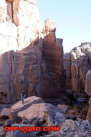 John climbs over some massive rocks in Sandstone Canyon, beautiful hoodoos tower in the background.