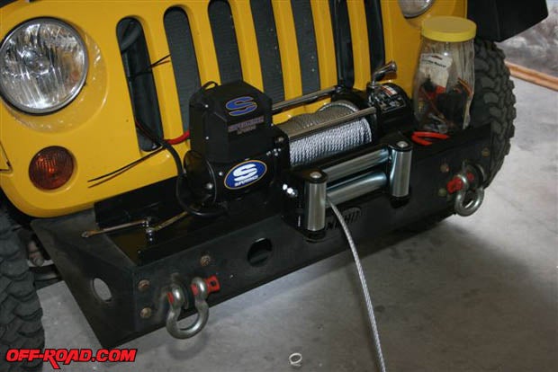 The winch is mounted and partially wired to the battery. It has an exposed circuit breaker that is designed to connect between the battery and the red power cable. If your winch is similarly equipped, youll need to insulate it carefully to avoid it grounding out during off-road travels. We had to pull out one layer of cable to access the captured square nut slots in the winchs case.