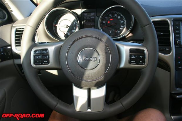 For 2011 Jeep has moved the cruise control onto the front of the Grand Cherokees steering wheel; the other side controls a phone system, and controls on the back side of the wheel control the audio system. On the dash, the vertical rectangular panel between the circular gauge bezels is an electronic information panel, giving such notes as average fuel economy, estimated distance to empty, etc.