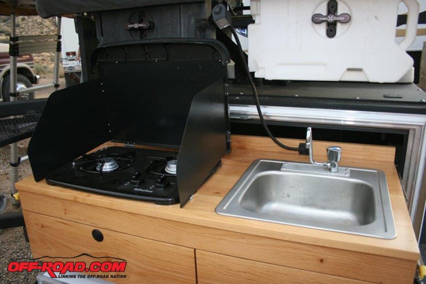 The galley contains a two-burner stovetop, a sink with hot water under pressure, and a gooseneck lamp.
