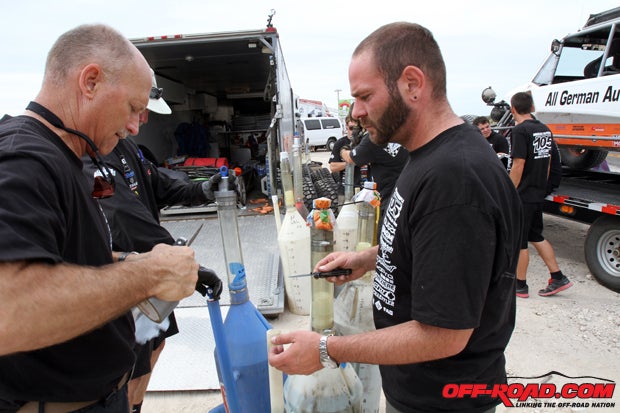 Driver of record for the #105 Class 1 car Tony Miglini helps the team prepare fuel cans for a pit stop.