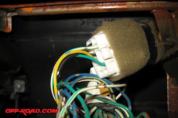 The most common location for the switch is the left most position on the top row of switches. Locate the unused terminator on the wiring harness. This might require some digging.  It can be located behind the radio or above the A/C controls. To identify it, look for a white female plug with a terminating male plug. It might be wrapped in foam with a green/silver jumper wire on it.