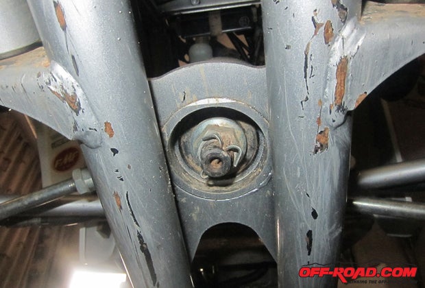 Once the tie rods are removed from the stem you will need to access the bottom of the steering stem. This is a big reason why we jacked the machine up off the ground. The large nut on the bottom of the stem should have a cotter pin in it as well, and you will use the same process as the tie rod ends to remove the pin.