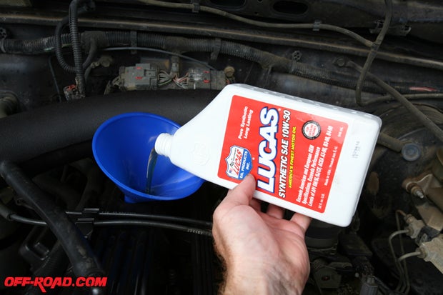 Using a funnel, we poured in the Lucas Oil Synthetic 10W30. Our Jeep TJ Wrangler  with the 4.0-liter engine calls for just under 6 quarts. We would typically leave it about .03 quarts low, replace the oil cap, and start the Jeep and let it idle for a minute. Turn off the engine, check the oil level and then pour in more if needed. Repeat the same steps until it is at the proper level, noting to not pour too much so as not to overfill the crankcase.