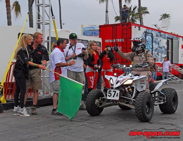 Elise and Roger Norman wave the starting flag to send an ATV racer off the line at the 2013 SCORE Baja 500. 