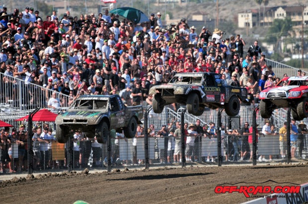 The Pro Lite class, including class winner Brian Deegan (#38), fly over the jumps on the front straight.