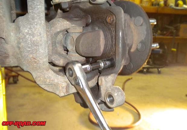 Use an 18mm socket and ratchet to loosen the four hub bolts. Dont remove them; just back them out about a quarter inch because youll need them to press the hub out of the knuckle.