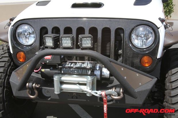 A Poison Spyder Brawler front bumper, which is fitted with a Warn winch and Rigid Industries floodlights. Just behind the bumper is Road Race Motorsports carbon-fiber grill.