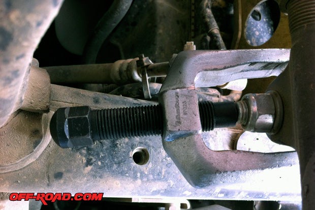 Using a wrench or socket, loosen the bolt from steering stabilizer on the drag link, but dont fully remove the nut. Use the tie-rod puller to detach the steering stabilizer from center link. 