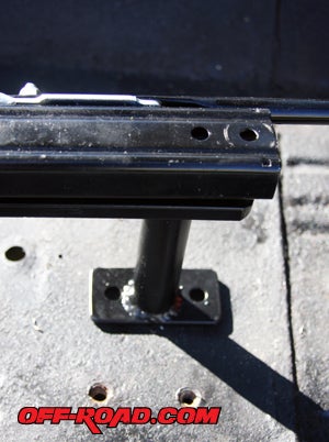 The passenger-side bracket is distinguished by a peg leg with tab. There are a total of four bolts holding down this seat bracket. 