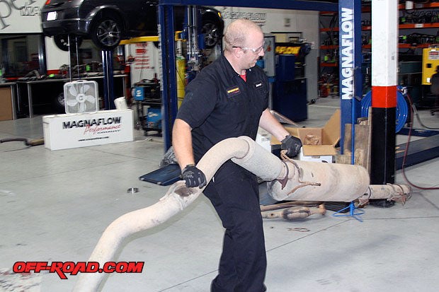 Jarrod Gunn wrestles the giant boa muffler and factory pipe from our Dodge diesel truck.